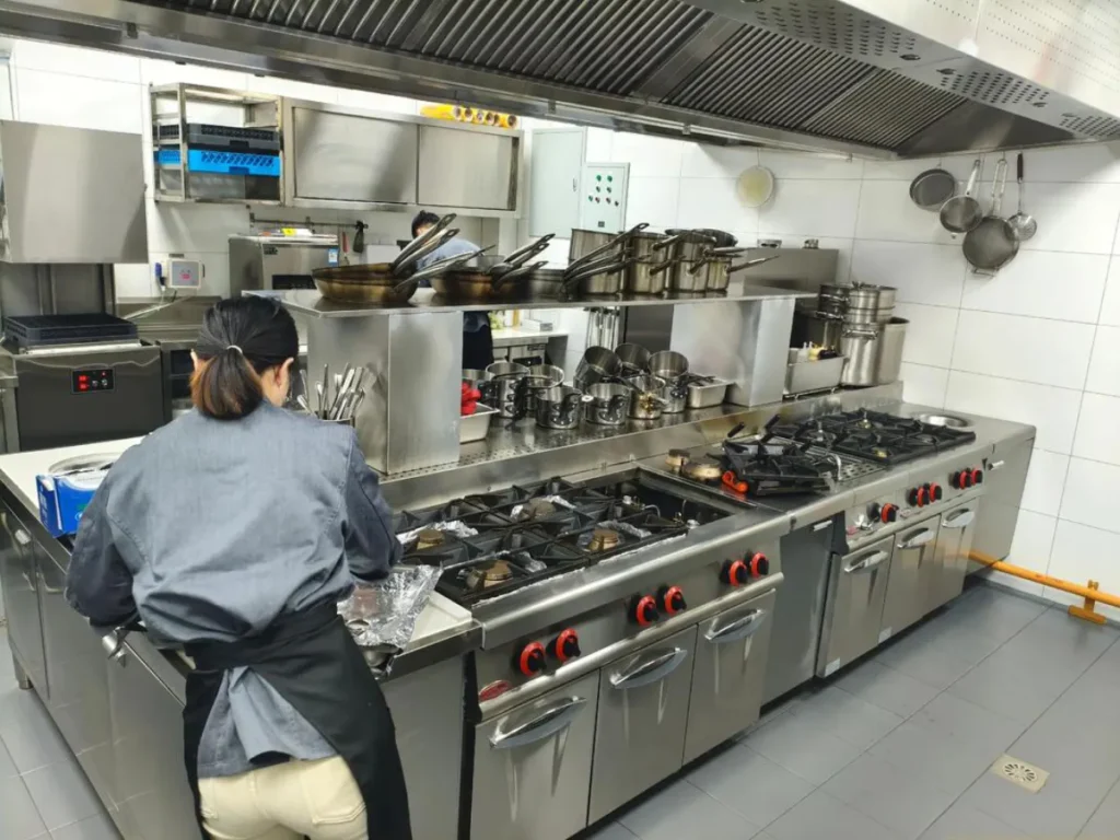 A professional chef preparing food in a stainless steel commercial kitchen