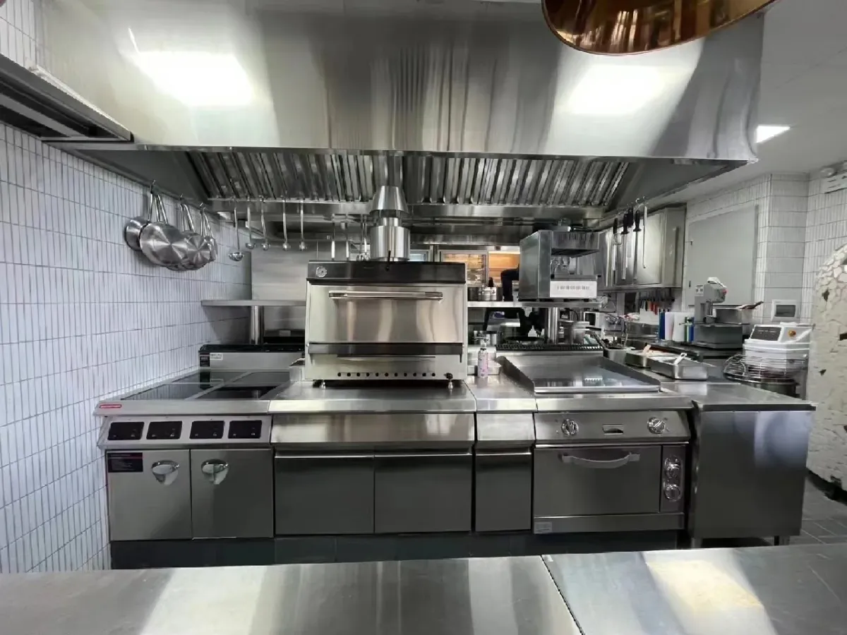 Commercial kitchen with stainless steel cooking appliances and stations protected by fire suppression