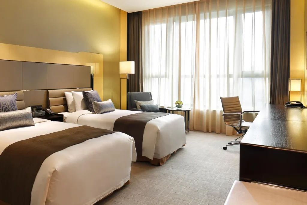 Modern hotel twin room with two beds and a desk area