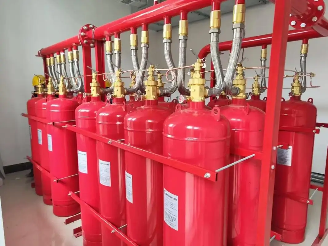 Bank of red CO2 fire suppression gas cylinders with flexible discharge hoses for industrial machinery protection
